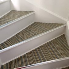 Stair treads fitted with striped wool loop carpet on the top tread with single ally door bars to the front and white painted risers.