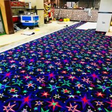 Glow in the dark fluorescent carpet in black with coloured stars. A printed nylon commercial carpet for extra heavy wear, fitted in an amusement arcade by Sargeant Carpets.