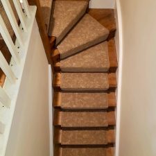 Brown patterned carpet on a staircase by Hugh Mackay in Country Oak from the Nature's Own range, with antique bronze stair rods by Stairods UK.