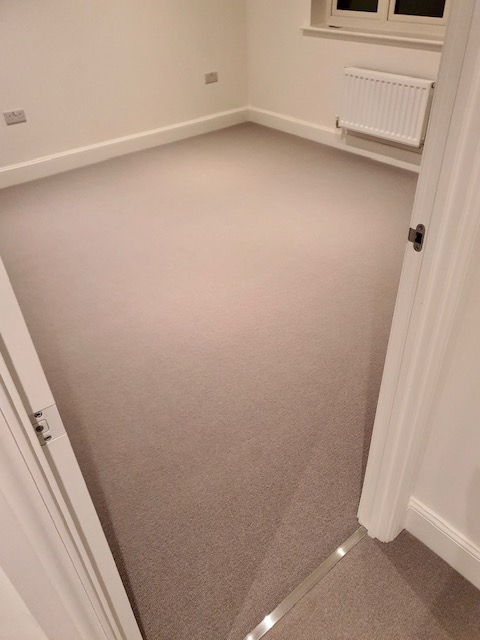 View of a bedroom fitted with light grey wool loop pile carpet by Sargeant Carpets.