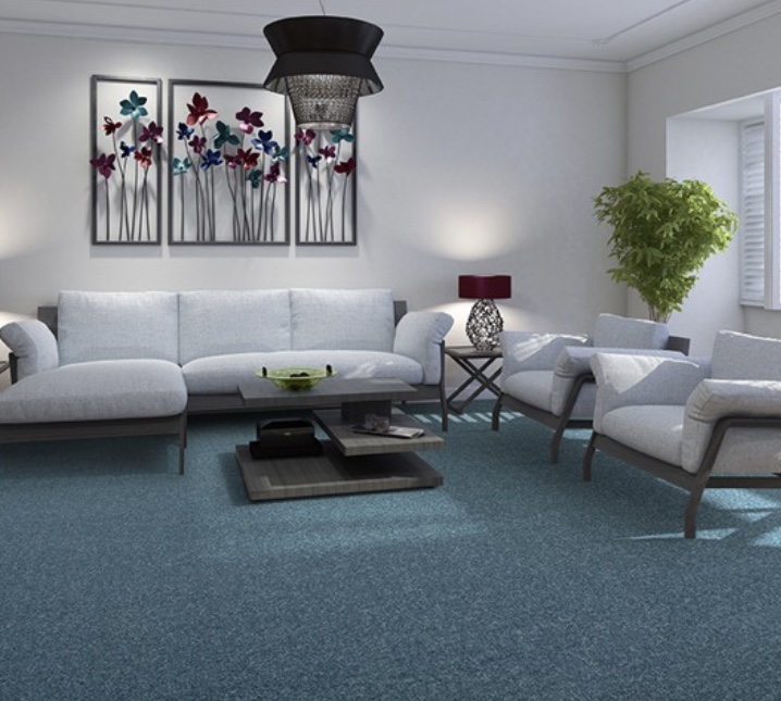 A living room featuring a sofa, chairs and table with neutral coloured secondary backed carpet.