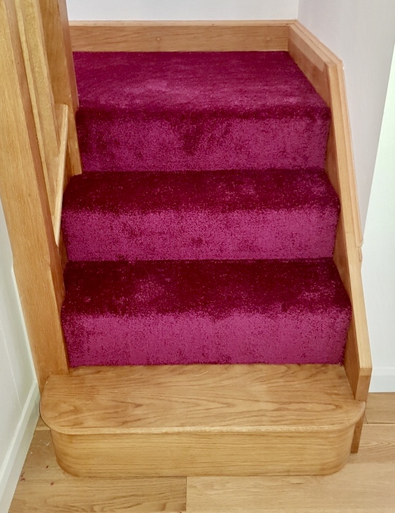 View up some stairs with wooden skirting board and carpet from the Kaleidoscope Carpet in Ruby pink
