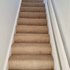 View up a flight of stairs fitted with a beige Polypropylene heather effect twist pile carpet, easy clean, bleach cleanable pile in Thatched Roof.