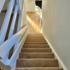 View down a flight of stairs fitted with a beige Polypropylene heather effect twist pile carpet, easy clean, bleach cleanable pile in Thatched Roof.