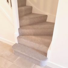 View up a staircase fitted with beige bleach cleanable polypropylene twist pile carpet from the Cormar Carpets Apollo Plus range in Homerton Grey