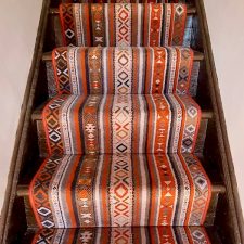 View of stairs fitted with a stripy, patterned wool Axminster carpet runner from the Quirky Stair Runners range in Tribe Passion.
