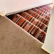View down stairs from a landing fitted with a stripy, patterned wool Axminster carpet runner from the Quirky Stair Runners range in Tribe Passion.