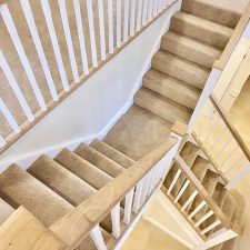 View of a flight of stairs fitted with a beige polypropylene twist pile carpet, bleach cleanable tri-coloured yarn.