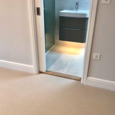 View towards a bathroom from a landing fitted with a beige New Zealand wool loop carpet in premium quality two-fold yarn.