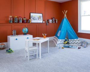 A child's playroom with blue tent, table and chair and storage with deep orange walls and grey carpet in the Grey Partridge colour.
