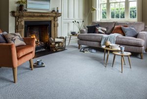 Living room with sofa, open fire, tables and occasional chair with a grey malabar tungsten carpet