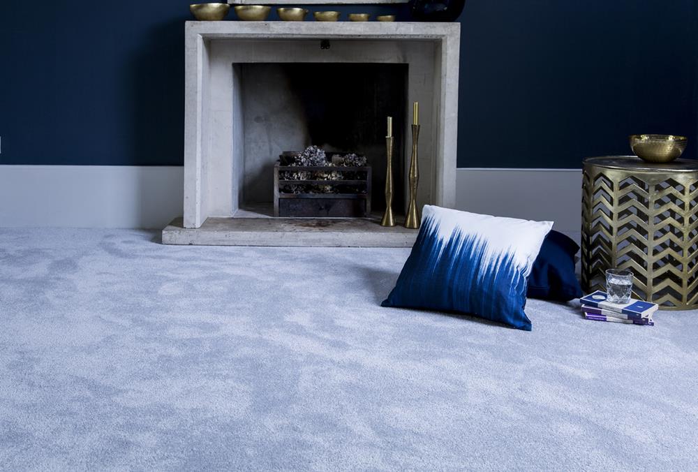 A living room with dark blue walls, open fireplace and cushions on a grey carpet from the Sensation range in Cape Diamond.