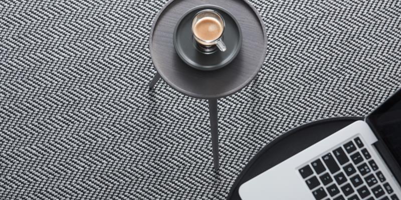 A living room herringbone flatweave carpet with table and laptop