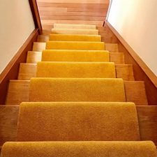 View down a staircase fitted with gold coloured wool/nylon pile moth proof carpet.