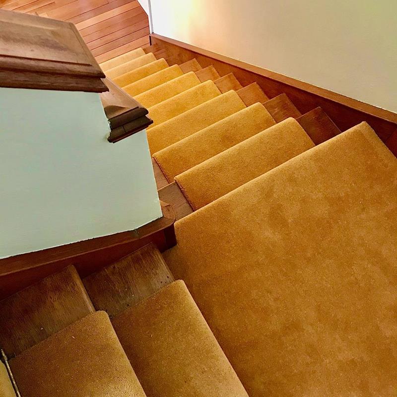 View down a staircase fitted with gold coloured wool/nylon pile moth proof carpet.