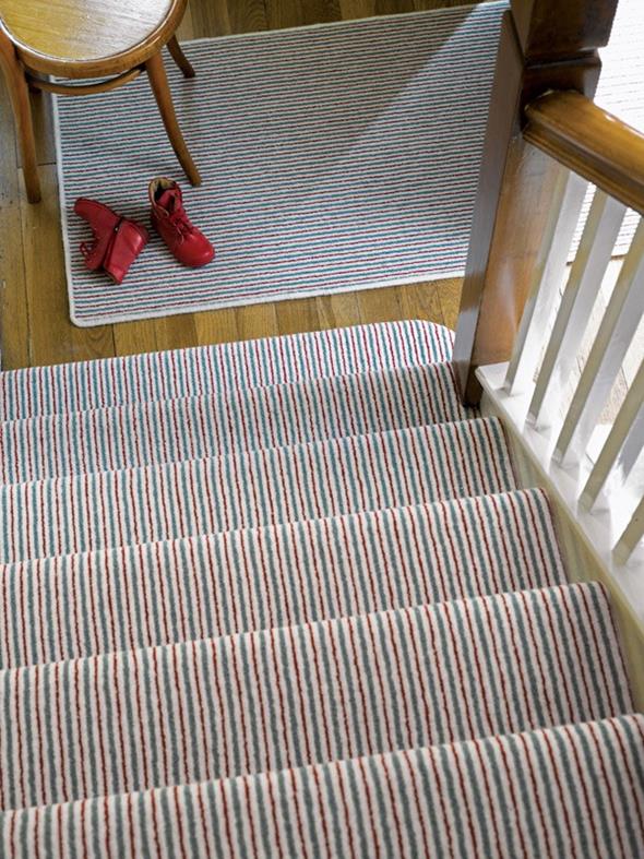 A view down stairs fitted with a stripy carpet from the Pinstripe range by Adam Carpets
