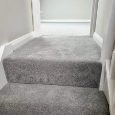 View of the top of a flight of stairs fitted with grey polypropylene twist pile carpet.