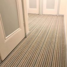 View of a landing floor which is covered with a velvet tufted carpet in a neutral striped colour