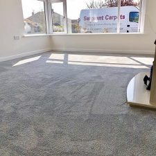 View of a lounge room fitted with a grey polypropylene saxony soft feel, bleach cleanable carpet. A large window looks outside onto the Sargeant Carpets van.