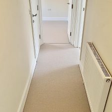 A hallway floor fitted with a New Zealand wool loop carpet in a light beige colour.