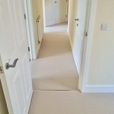 View out of a bedroom onto a hall fitted with a New Zealand wool loop carpet in a light beige colour.
