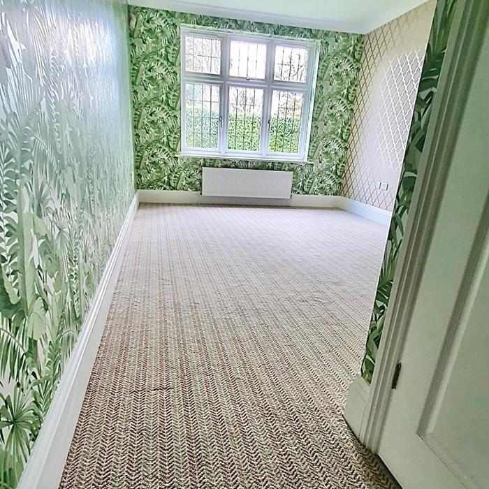 Bedroom with brightly coloured leaf design wallpaper and Axminster carpet with herringbone design in neutral colours