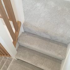 View of a landing and the top of a flight of stairs fitted with a light grey Polypropylene saxony carpet.