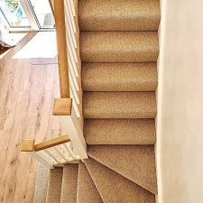 View down a flight of stairs fitted with a warm honey coloured wool loop, moth resistant carpet.