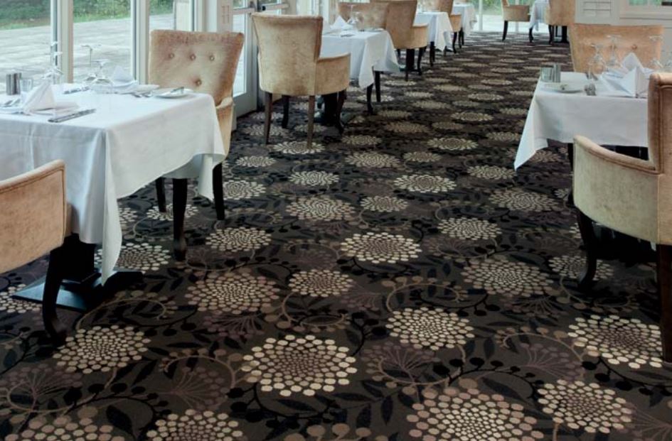 A commercial dining room with tables laid for service and a floral carpet by Ulster Carpets.