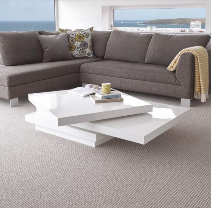 A living room fitted with the Strond carpet, with windows overlooking the ocean
