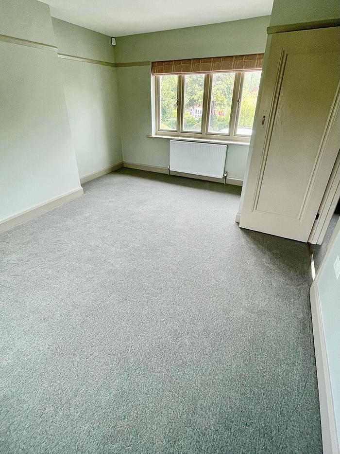 An empty bedroom fitted with a grey/green wool and nylon twist pile carpet.