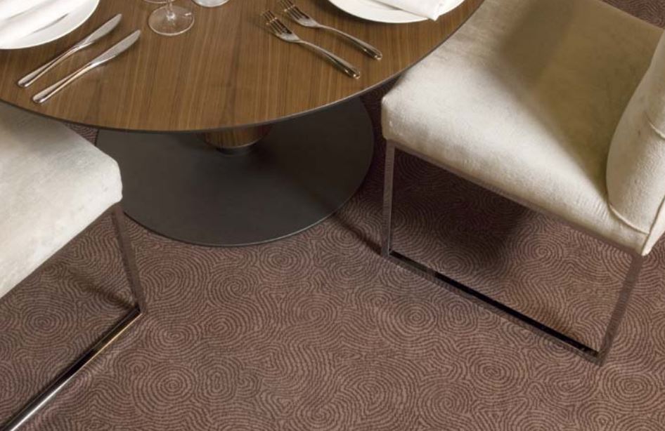A dining table and chairs on a swirly taupe carpet.