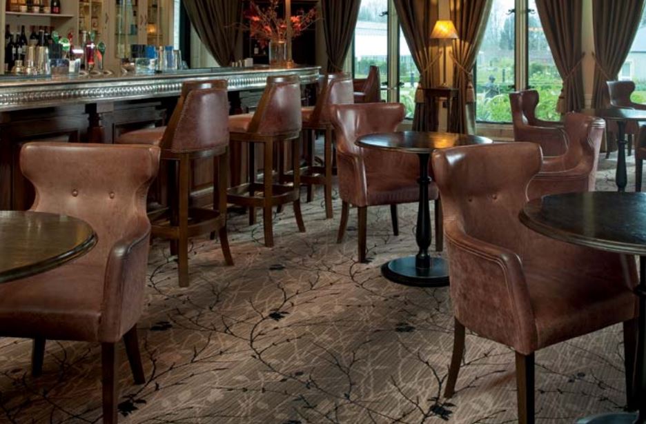 A bar with tables and chairs and a patterned carpet in shades of brown