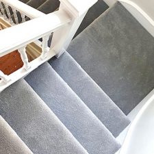 View down a flight of stairs fitted with a grey polypropylene bleach cleanable, fade resistant domestic carpet.