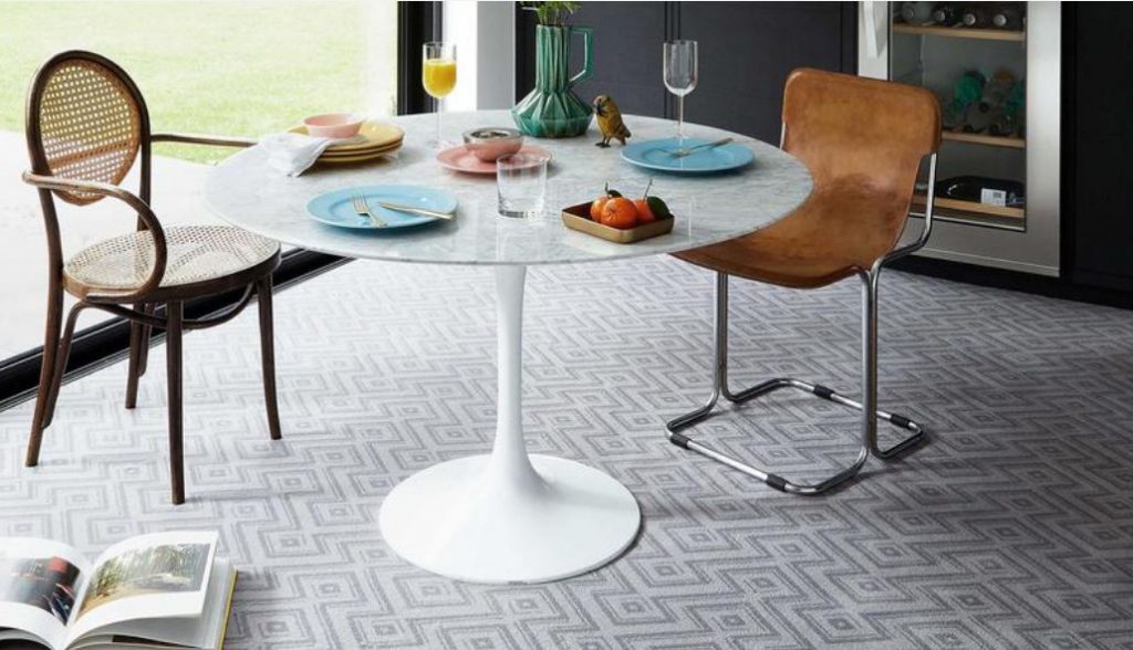 A dining table and chairs on a patterned carpet from the Perpetual Textures range.