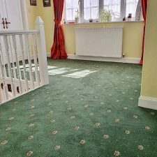 View of a landing fitted with a green patterned, heavy wear, woven Axminster carpet.