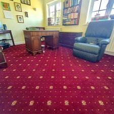 A deep red woven axminster patterned carpet fitted in a living room.