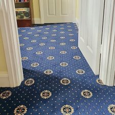 A patterned woven Axminster blue carpet fitted in a hallway and living room.