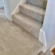 View of the bottom of a flight of stairs fitted with a grey polypropylene Saxony carpet
