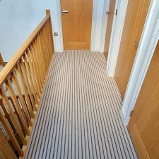 View of a landing fitted with a neutral striped runner carpet made from British wool and is moth resistent.