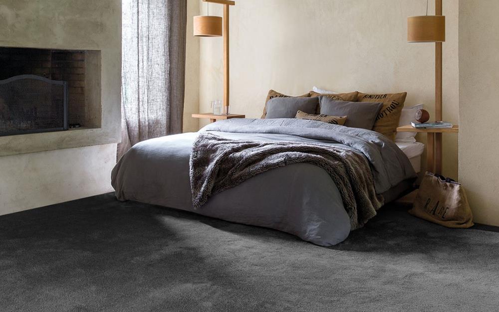 Bedroom with double bed and grey bedding, beige walls and grey carpet
