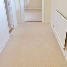 View of an empty hall fitted with a light beige berber twist pile heavy domestic carpet.