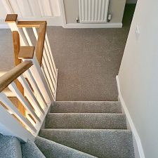 View down a flight of stairs to a hallway below. The stairs are fitted with a Polypropylene twist pile moth proof carpet