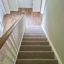 View down a flight of stairs to a front door. The stairs are fitted with a Polypropylene twist pile moth proof carpet
