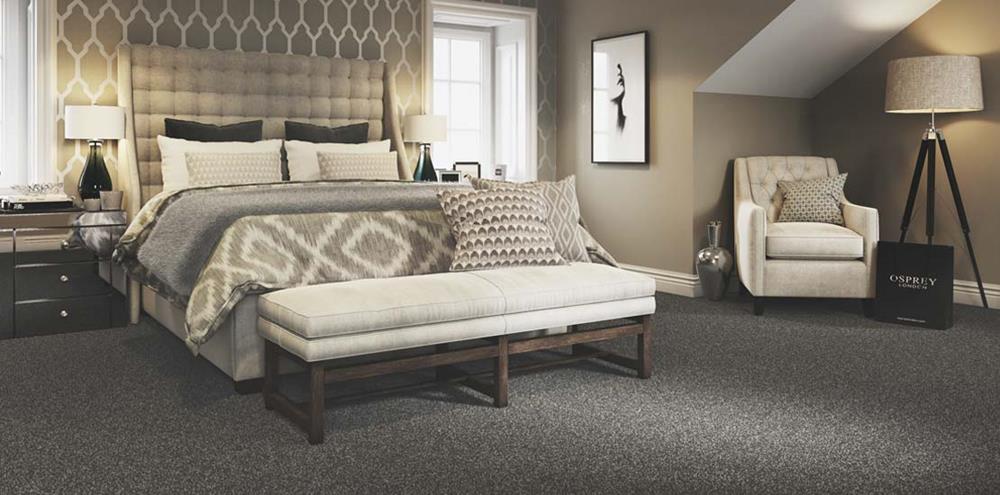 A smart bedroom with neutral shades of decor and a plain charcoal grey carpet