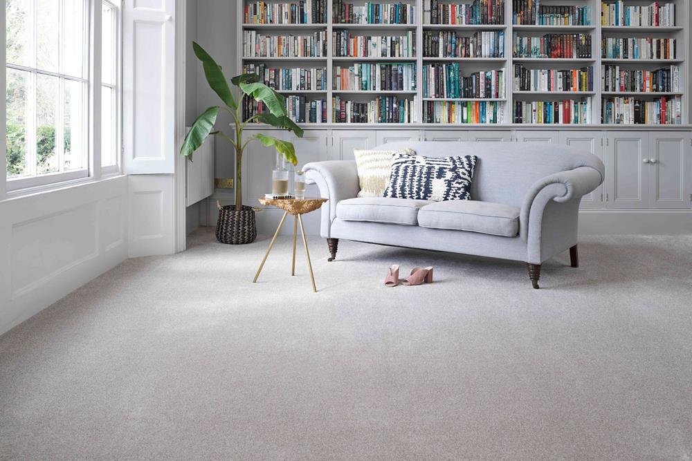 A living room lined with bookshelves painted grey, a grey couch and light grey carpet in an Ermine shade.