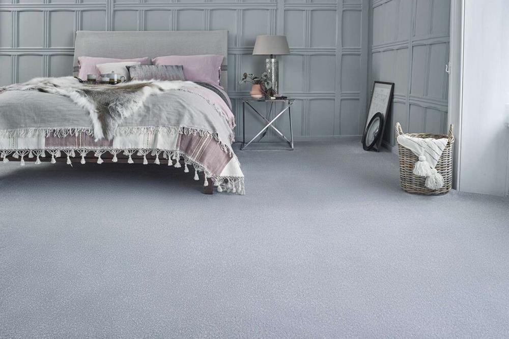 A bedroom with grey painted panelled walls, grey and lilac soft furnishings and light grey stainfree carpet