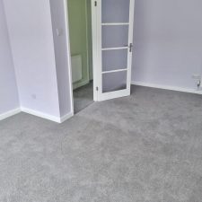 A living room with grey painted walls and a grey wool/synthetic moth resistant carpet.