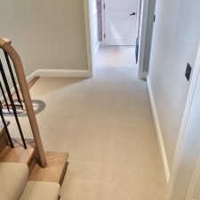 View of a hallway fitted with pale beige wool loop carpet.