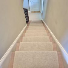 View down a flight of stairs fitted with pale beige wool loop carpet.